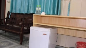 A small white refrigerator, a wooden bench, a blue curtain, and a tiled floor.
