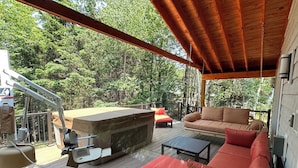 Una terraza techada al aire libre con una parrilla, un sofá y una mesa.