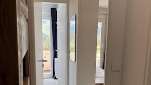 A hallway with a wooden floor leading to a bedroom with a bed and a view of a garden. - 150m from resort center, Ground floor, balcony, tv, 34m², Avoriaz (Avoriaz)