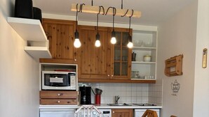 A modern kitchen with wooden cabinets, a built-in microwave, and a dining table set for four. - 150m from resort center, Ground floor, balcony, tv, 34m², Avoriaz (Avoriaz)