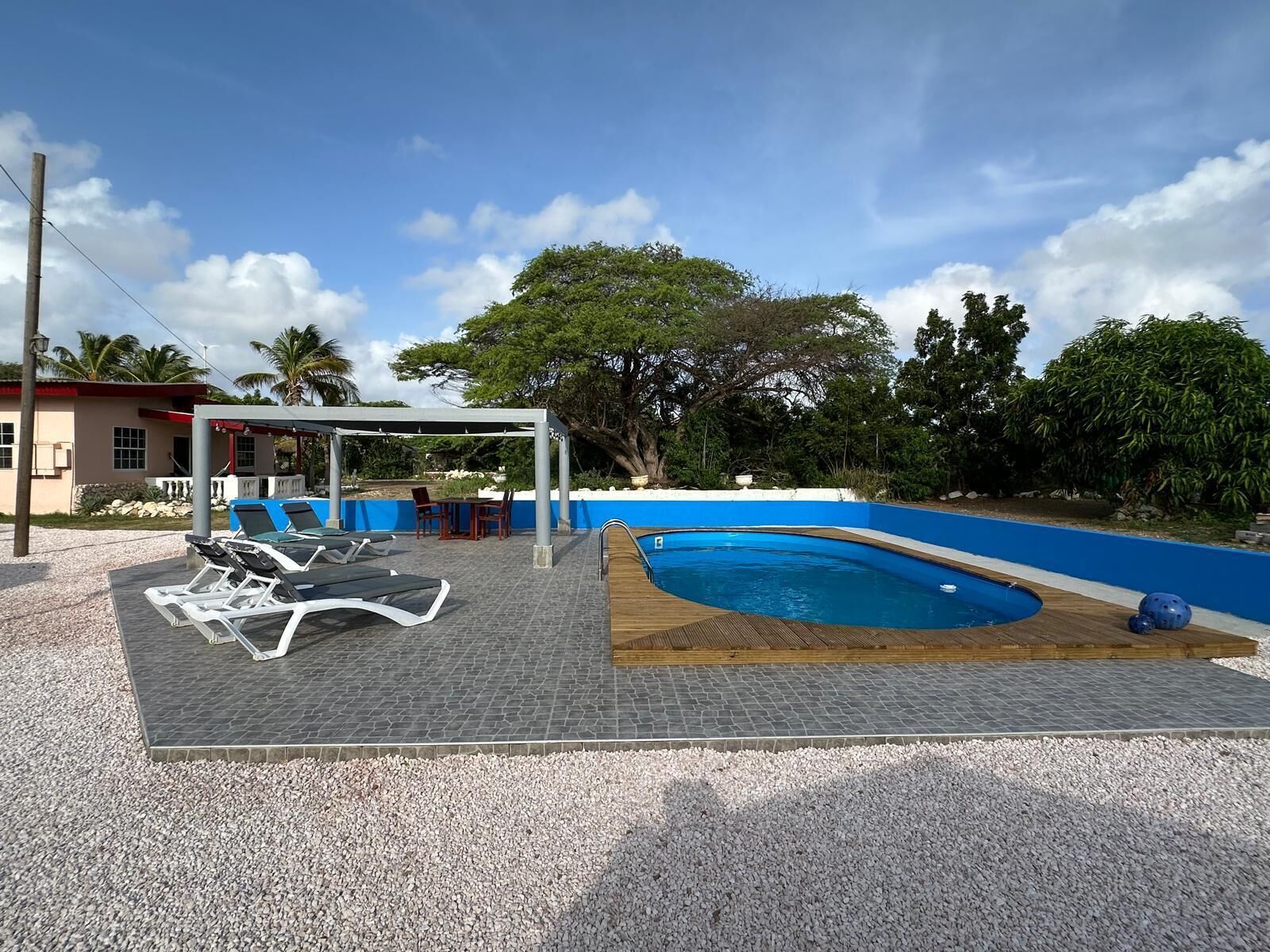 A swimming pool with lounge chairs and a covered seating area.