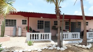 Un edificio con techo rojo, barandillas de balcón blancas y suelo de grava.