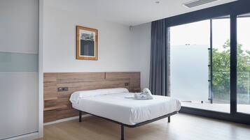 A modern hotel room with a wooden headboard, a large window with a view, and a neatly made bed with towels.