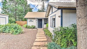 A residential property with a stone pathway leading to a front door, surrounded by greenery and a wooden fence. - Cozy Cottage in the Heart of Lakeside (Lakeside)
