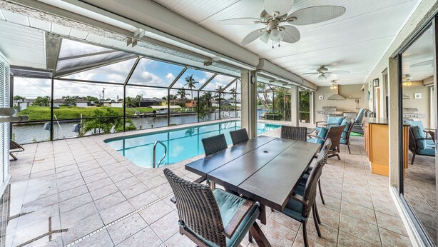 A covered outdoor patio with a pool, dining area, and ceiling fans.