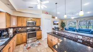 A modern kitchen with wooden cabinets, a black countertop, and a tiled backsplash.