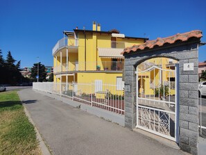 A two-story yellow building with a white gate and a stone pillar. - Terrace Apartment by Tempovacanza (Marina di Andora)
