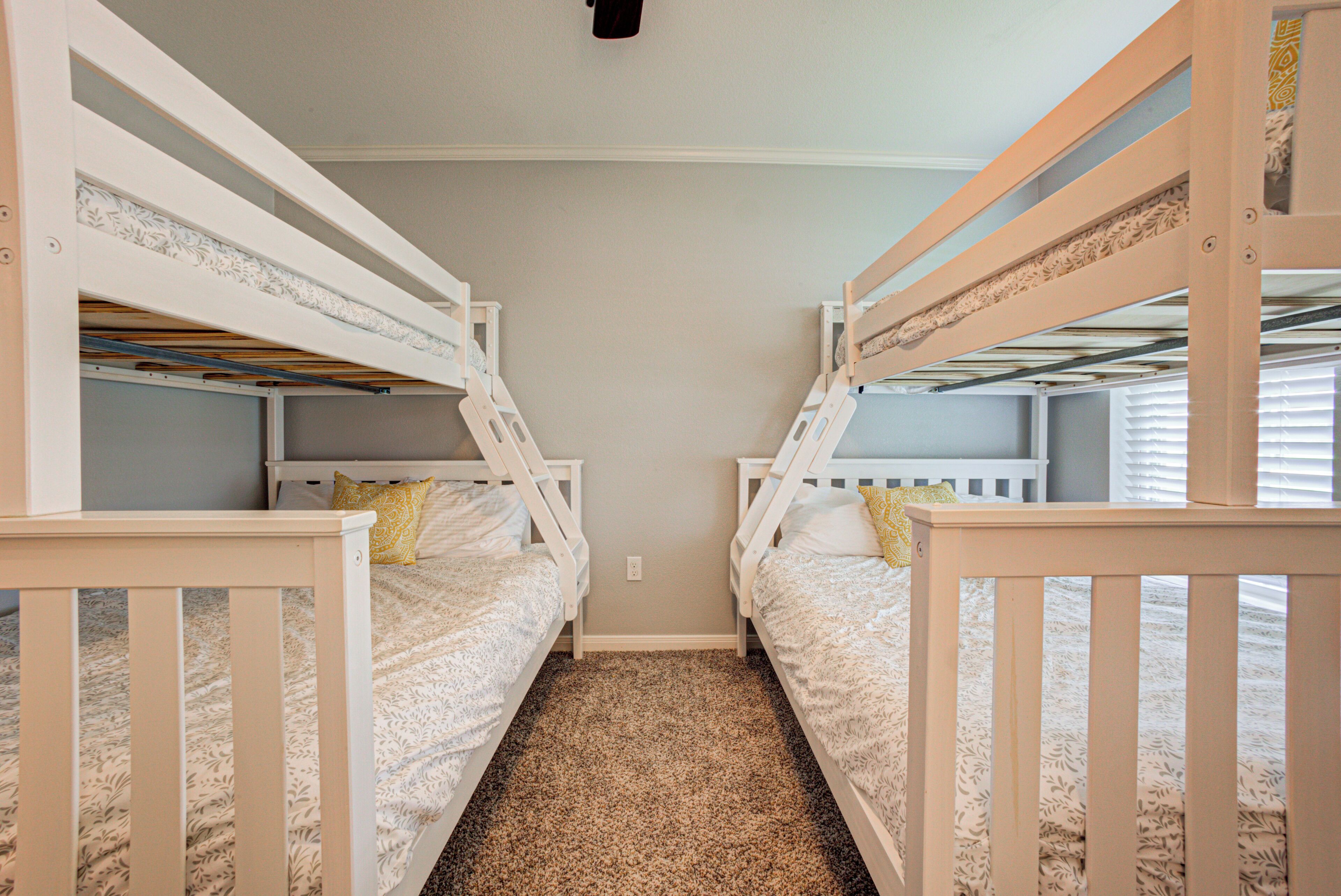 A room with bunk beds, carpeted floor, and a plain wall.