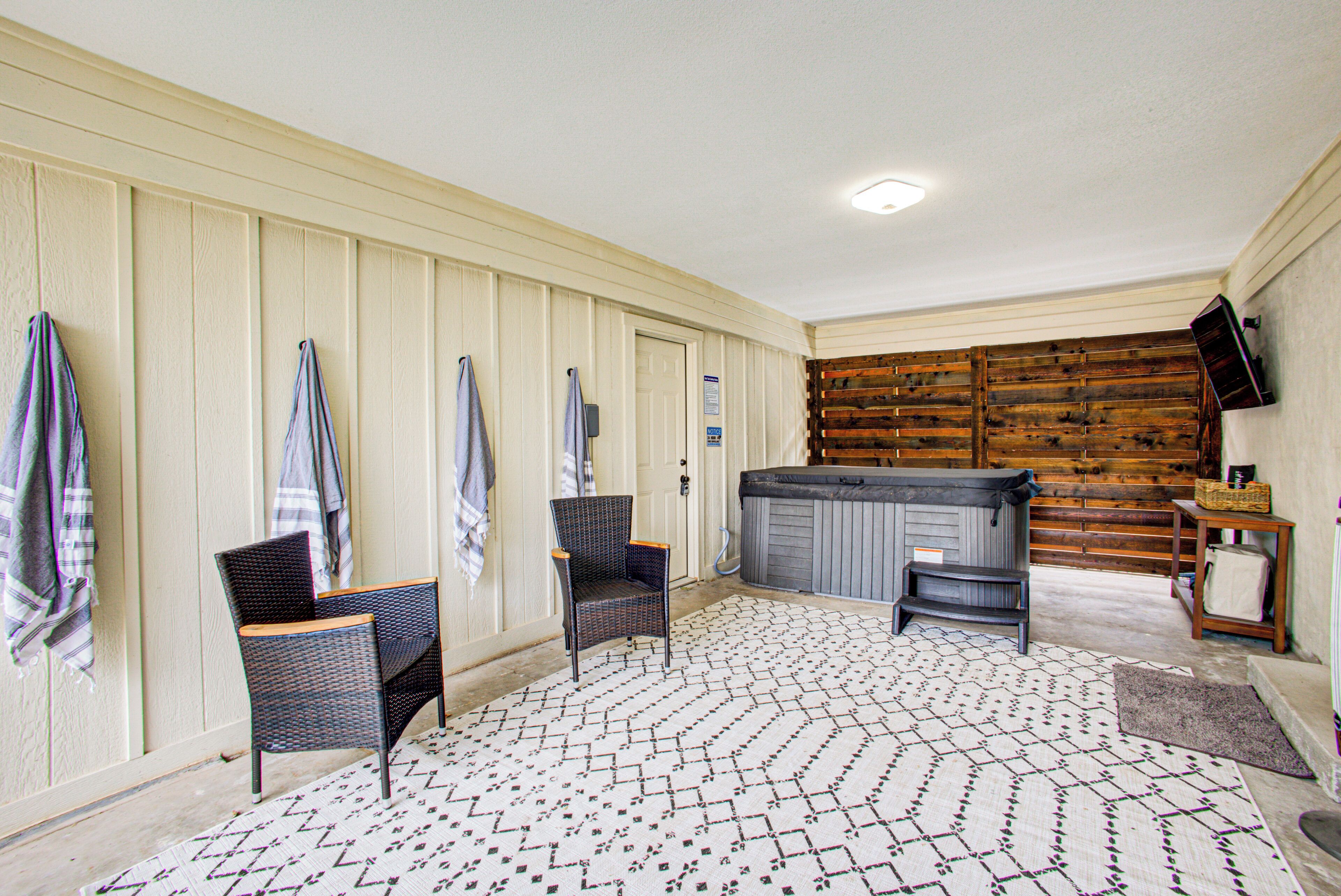A room with two wicker chairs, a hot tub, and a patterned rug.