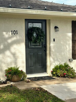 A house with a dark front door, number 101, a wreath on the door, and two flower pots on either side of the entrance. - Casablanca Waco (Waco)