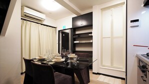 A modern dining area with a glass table, dark chairs, and a black cabinet.