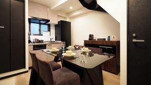 A modern kitchen with a dining table set for six, equipped with a microwave, oven, and a coffee machine.