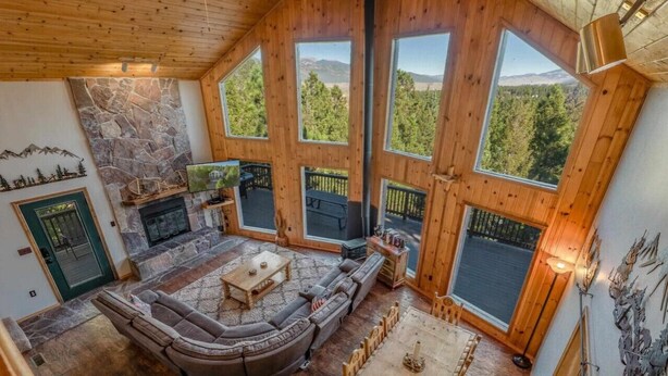 Un salón amplio con chimenea de piedra, ventanas grandes y una zona de estar acogedora.