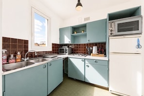A compact kitchen with teal cabinets, a microwave, a toaster, and a refrigerator.