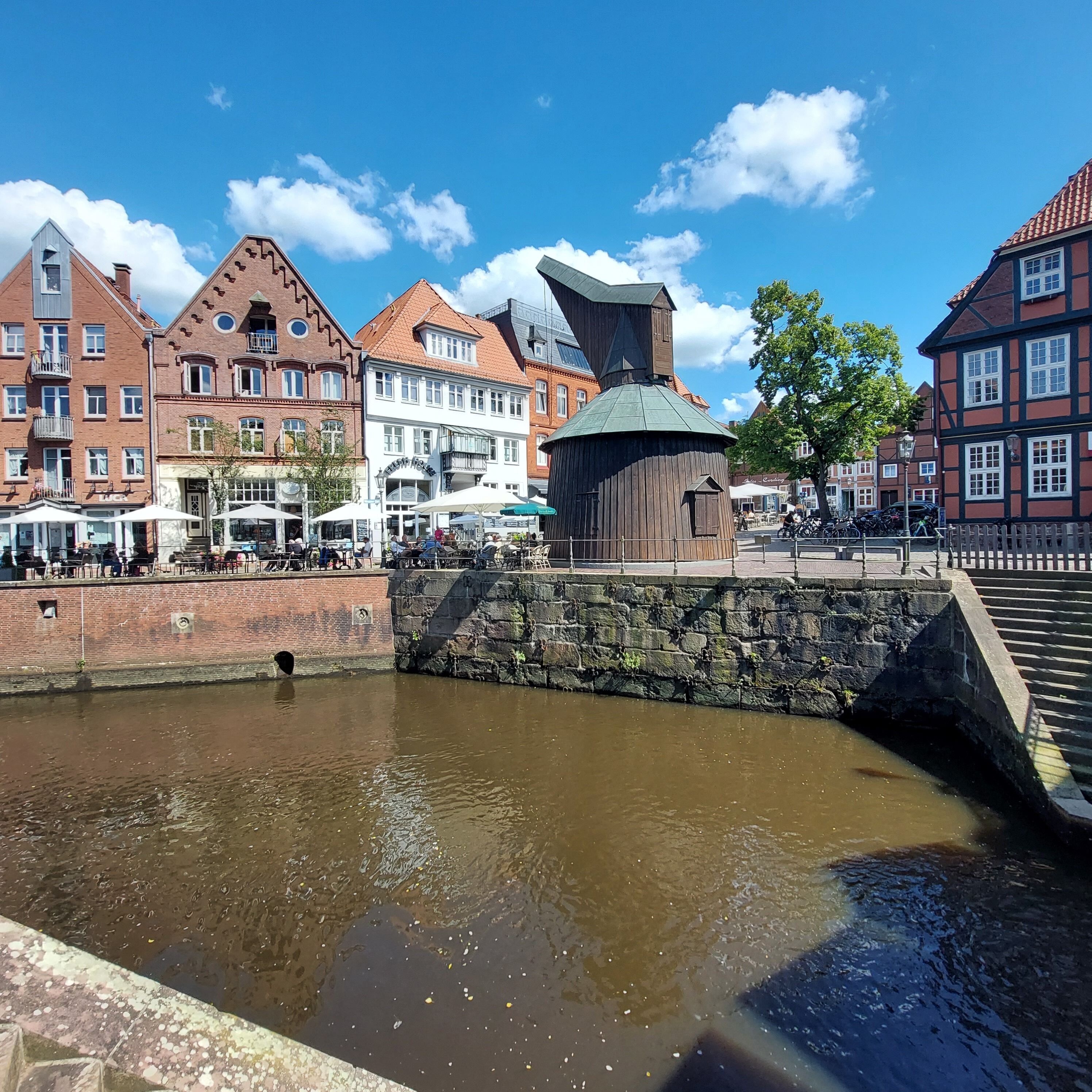 A historic building with a unique architectural design, a stone bridge, and a calm water body.