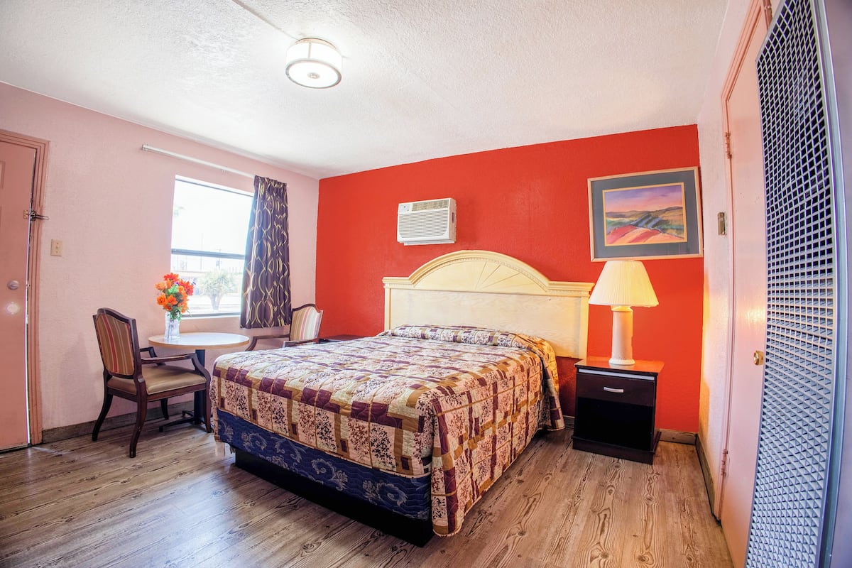 A bedroom with a bed, a desk, and a chair.