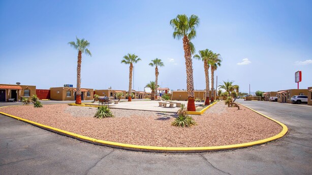 A parking lot with palm trees and a building with a red roof. - Sands Motel By OYO El Paso Near Airport (El Paso)
