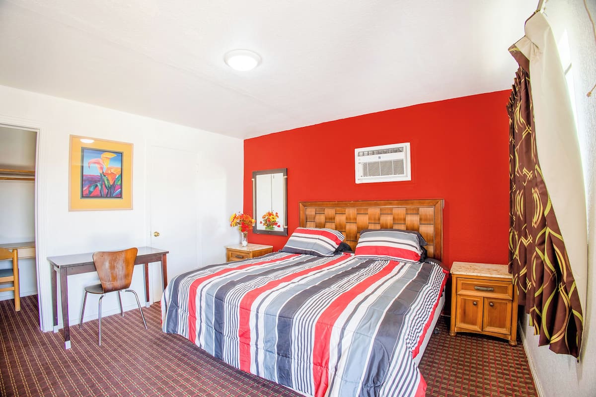 A hotel room with a bed, a desk, a chair, and a nightstand.