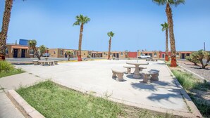 A courtyard with palm trees, outdoor seating, and a building with multiple doors. - Sands Motel By OYO El Paso Near Airport (El Paso)