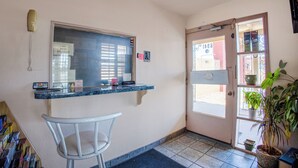 A reception area with a desk, a chair, a phone, and a door leading outside. - Sands Motel By OYO El Paso Near Airport (El Paso)