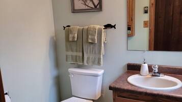 A bathroom with a toilet, sink, and a framed picture on the wall.
