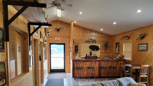 A cozy cabin interior with a bar area, wooden walls, and a sofa. - The Lodge (Cable)