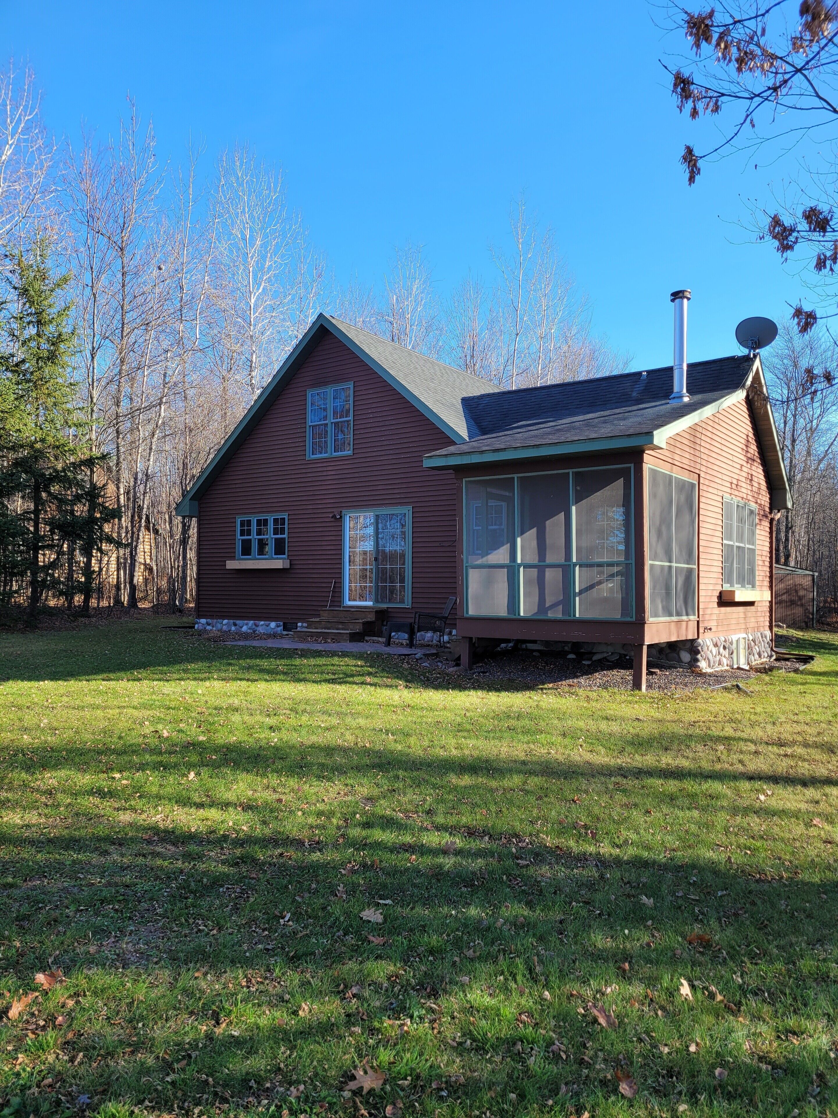 A two-story house with a large front porch and a satellite dish on the roof.