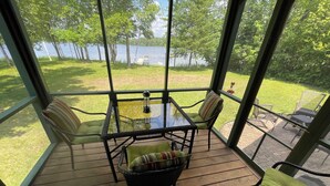 A covered outdoor seating area with a table and chairs, overlooking a lake. - Luck Charlie Lodge (Winter)