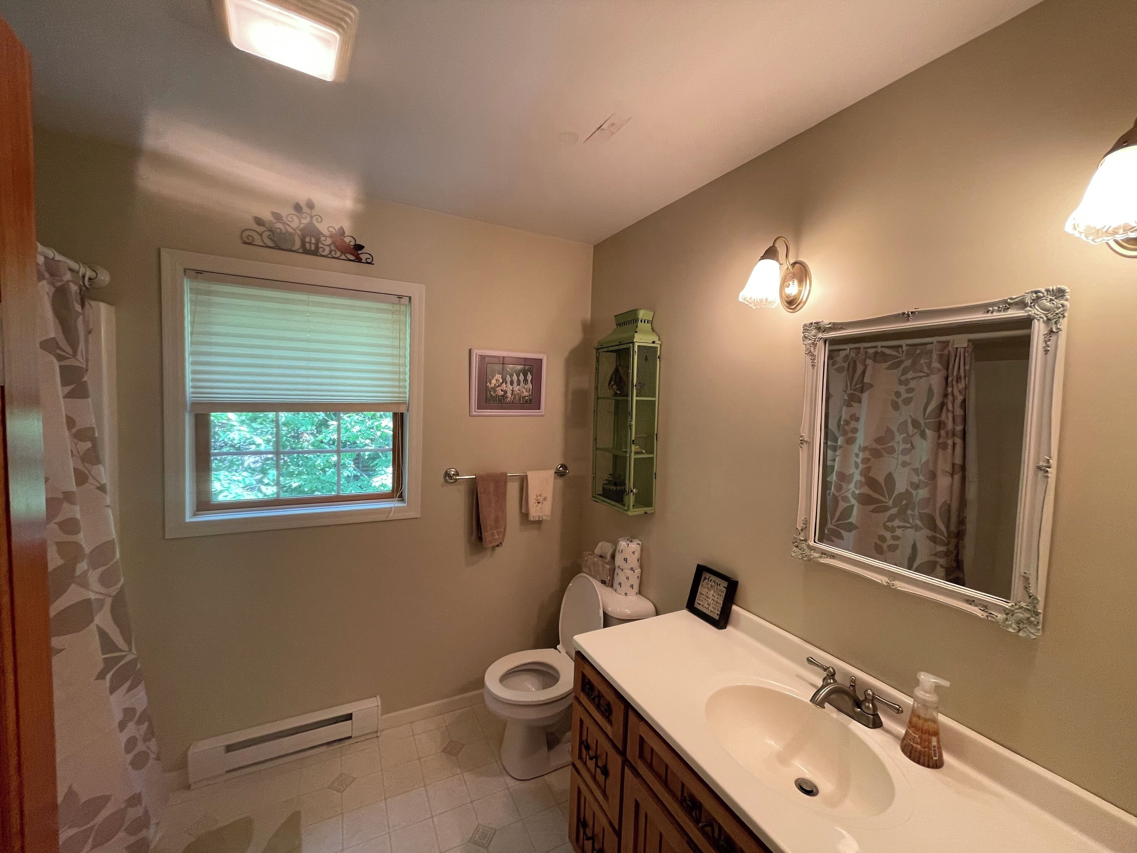 A bathroom with a toilet, sink, and window.
