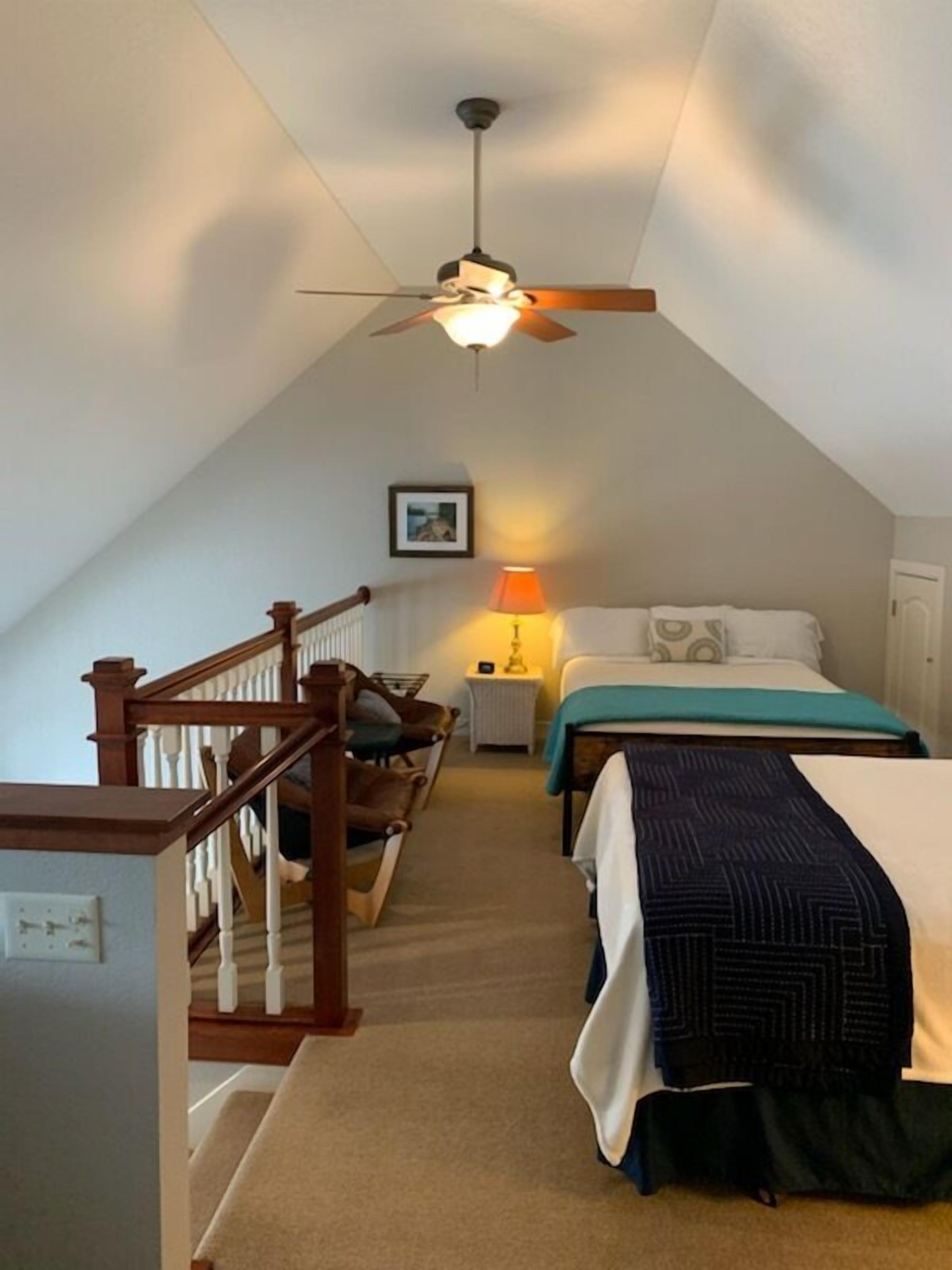A bedroom with a bed, a nightstand, a lamp, and a ceiling fan.
