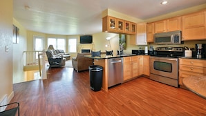A spacious kitchen with wooden cabinets, a stainless steel refrigerator, and a built-in oven. - Unit 109 2 Bdrm/ 2 BA (Birchwood)