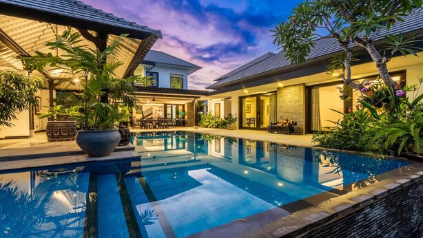 A modern pool area with a clear pool, surrounded by potted plants and a well-lit outdoor seating area. - 3-Bedroom Kejora 12 (Denpasar)
