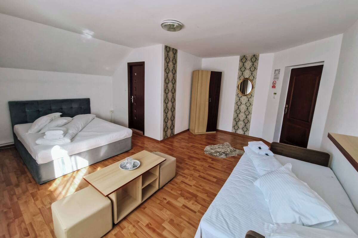Une chambre d’hôtel avec un lit, un canapé, un plancher en bois, une armoire et un miroir.