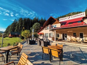 An outdoor seating area with tables and chairs, a pool, and a building with a red roof and a sign reading "Complex Caprioara Restaurant". - Complex Caprioara Toplita (Toplita)