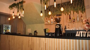 Eine Bar mit hängenden Lampen, einer Kaffeemaschine und Regalen mit Flaschen.