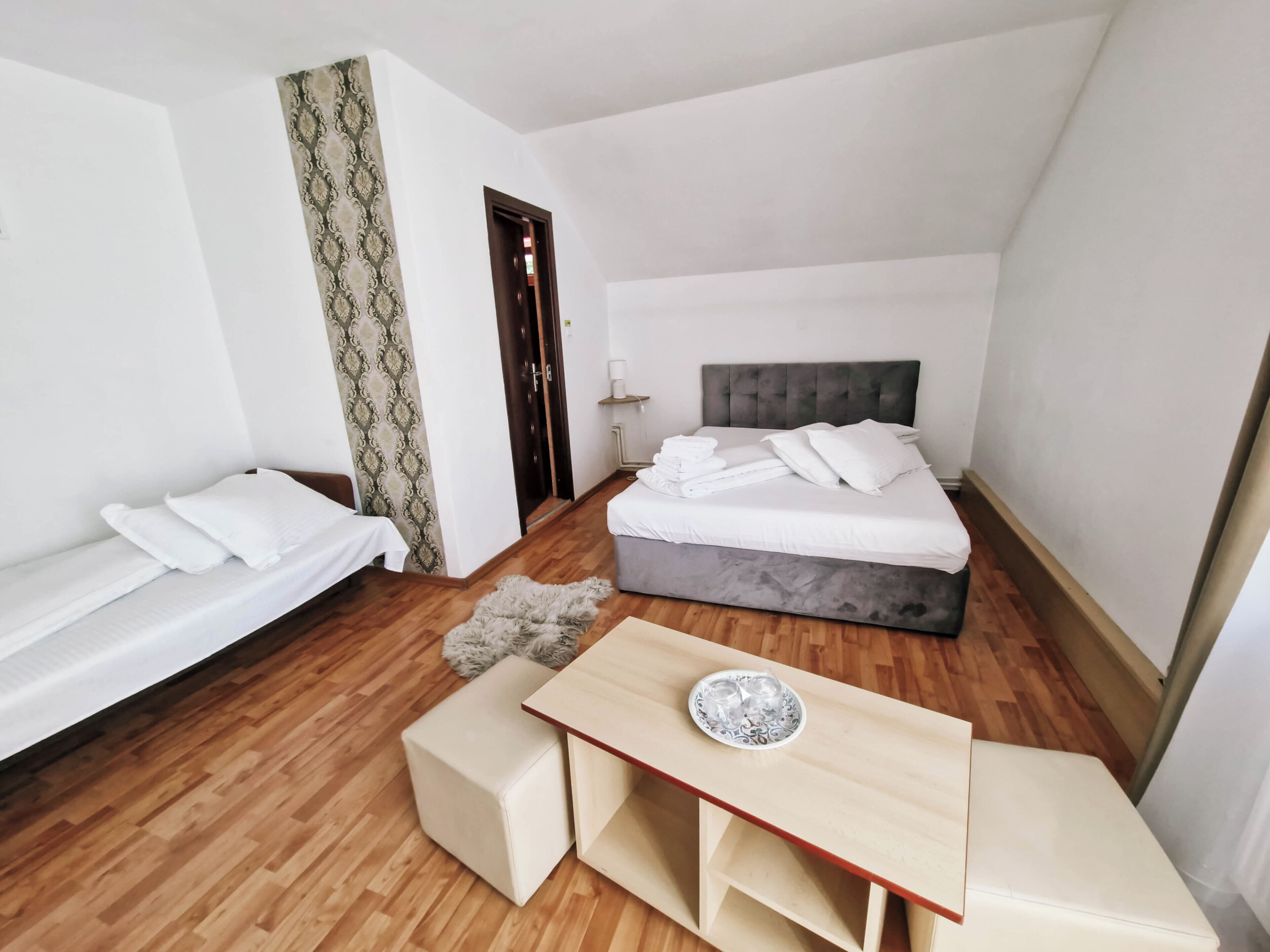 Une chambre d’hôtel avec un lit, un canapé, une petite table et un rideau à motifs.
