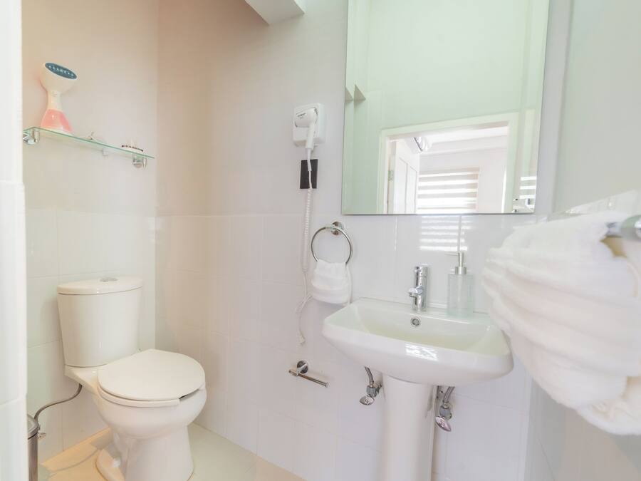 A bathroom with a toilet, sink, and a mirror.
