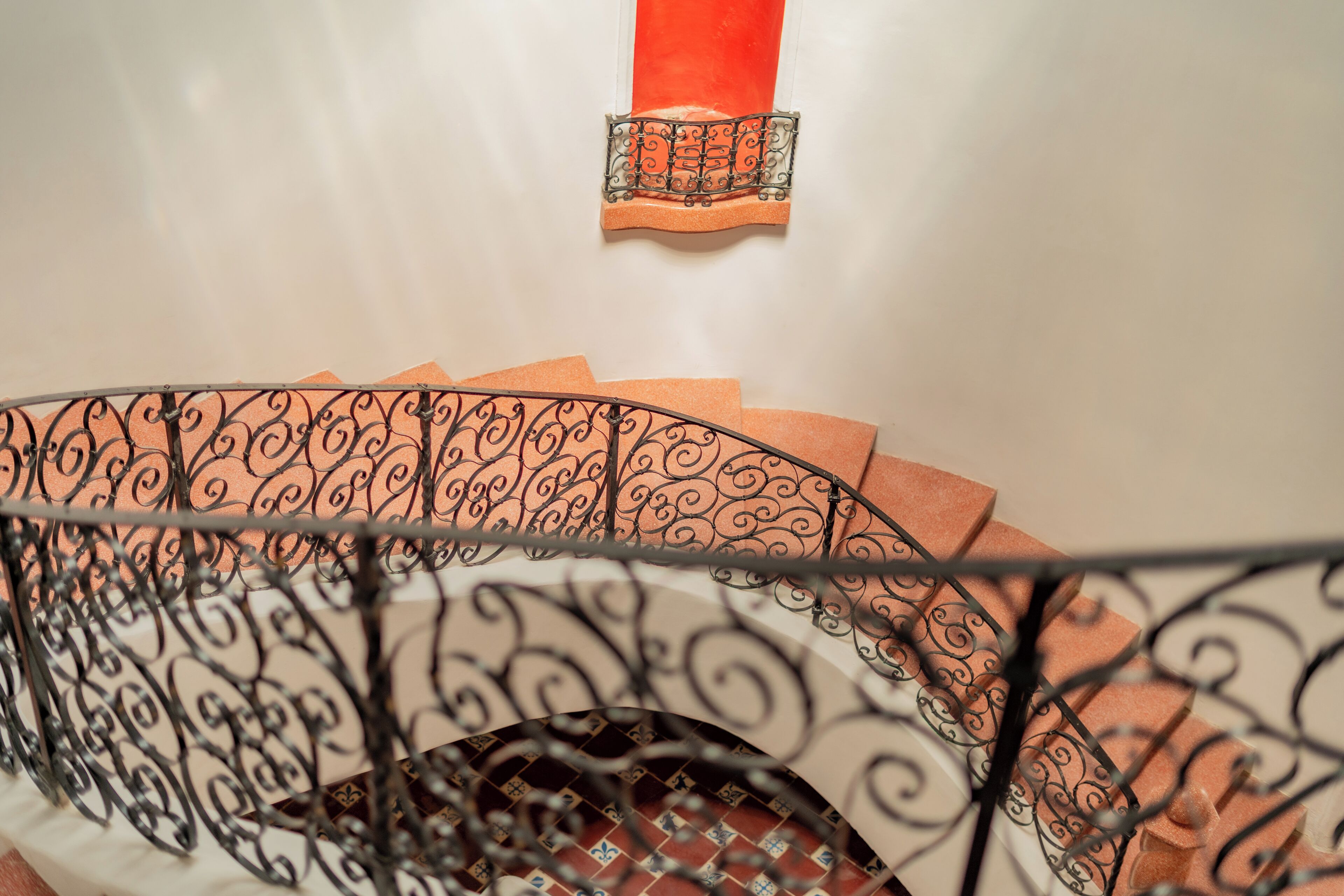 A staircase with ornate metal railings and a red accent wall.