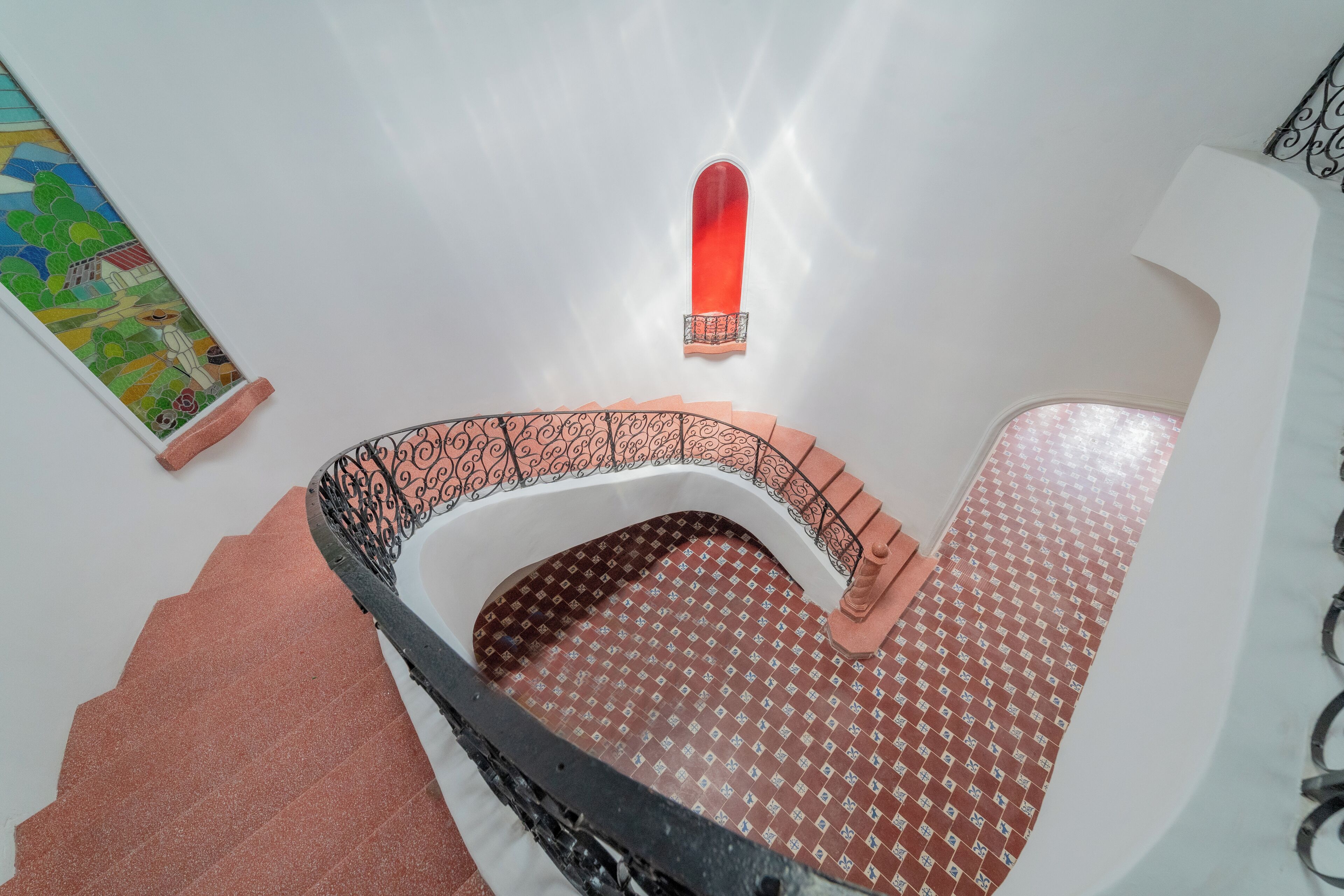 Una escalera de caracol con suelo estampado y pared roja decorativa.