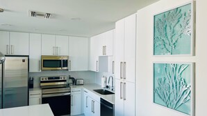 Eine moderne Küche mit weißen Schränken, Edelstahlgeräten und zwei gerahmten Bildern an der Wand.