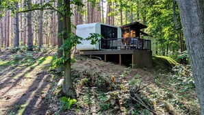 A forest cabin with a deck and a white RV. - Hidden Gem Tiny House, Outdoor Screened-In Kitchen (Sears)