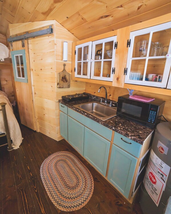 A compact kitchen with wooden cabinets, a sink, a microwave, and a refrigerator.