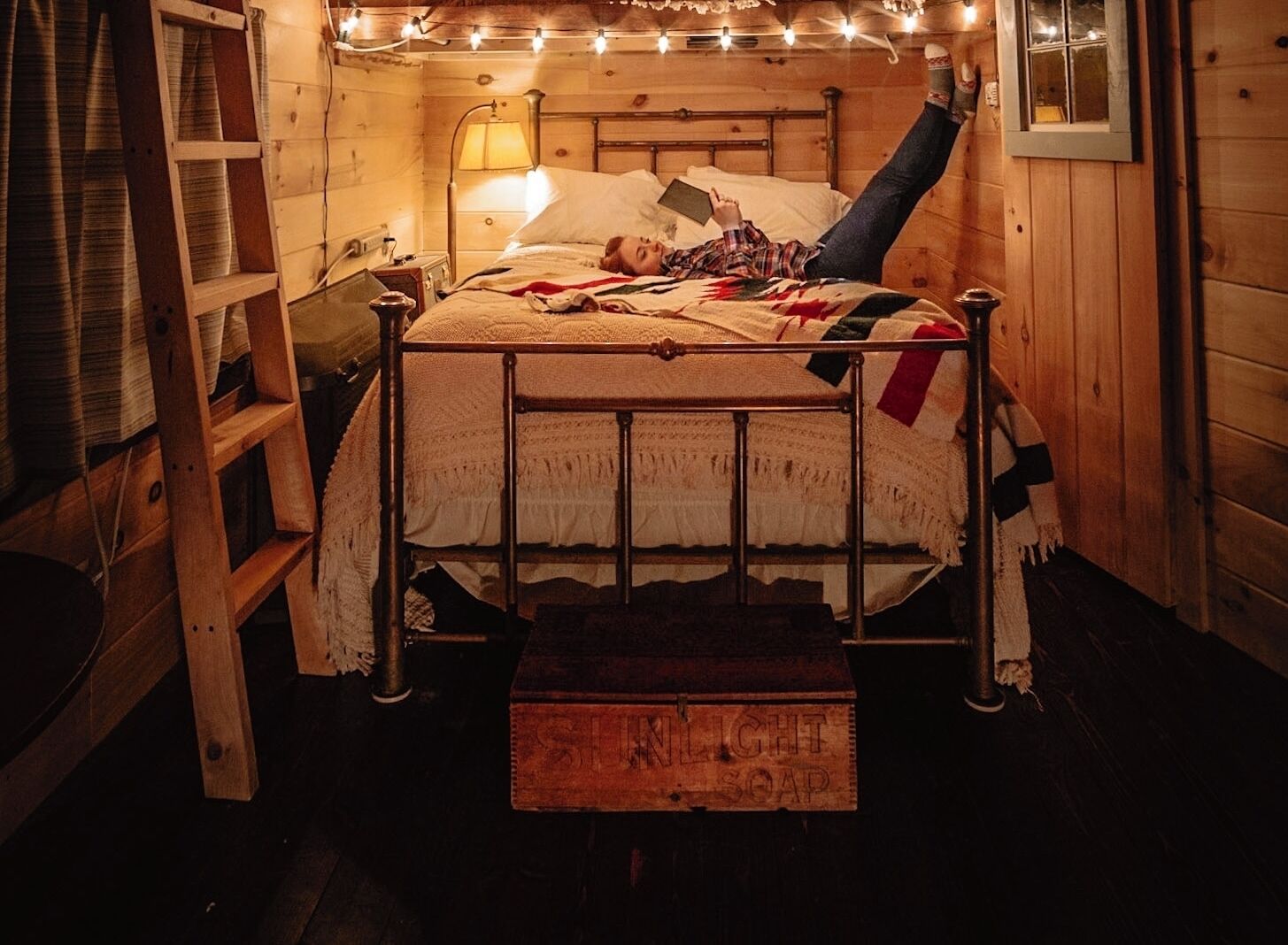 Ein gemütliches Schlafzimmer in einer Holzhütte mit einem Metallbettgestell, einer Nachttischlampe und einem Regal mit einer Lampe.