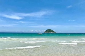 A beach with clear water, a small island, and a boat. - Shenzhen Xiyong Sanke Xiaoshu Homestay (Shenzhen)