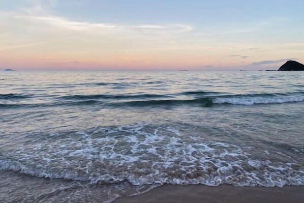 A beach with gentle waves and a distant view of a small island. - Shenzhen Xiyong Sanke Xiaoshu Homestay (Shenzhen)