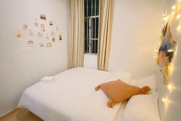 A bedroom with a bed, a window with curtains, and a wall with pictures. - Shenzhen Xiyong Sanke Xiaoshu Homestay (Shenzhen)