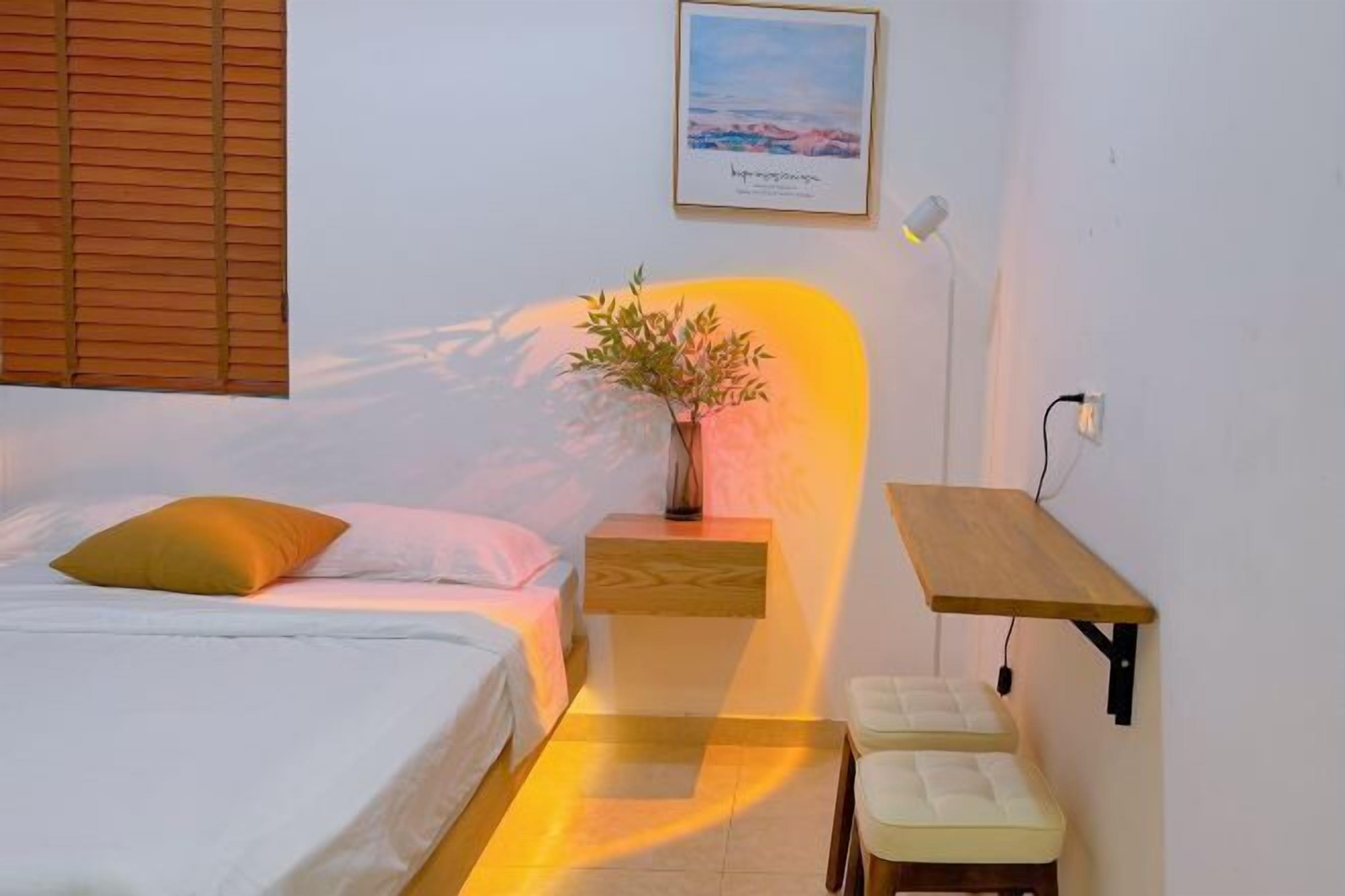 Een slaapkamer met een bed, nachtkastje, lamp en een klein houten tafeltje.