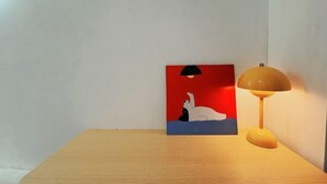 A wooden table with a painting and a lamp. - Shenzhen Xiyong Sanke Xiaoshu Homestay (Shenzhen)