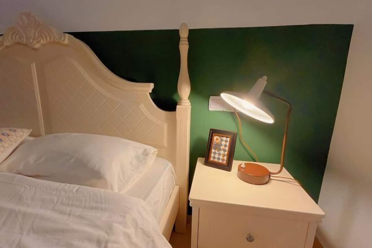 A bed with a headboard, a bedside table with a lamp, and a framed picture.