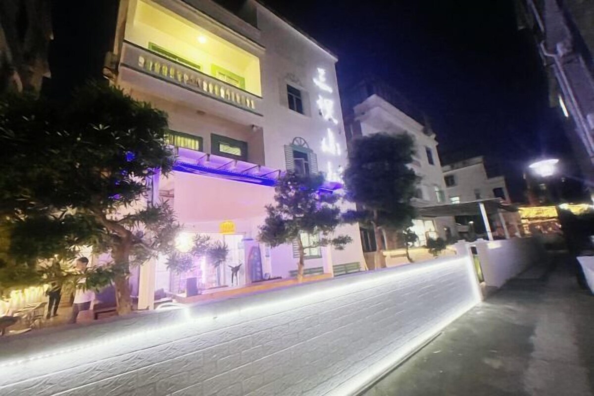 Un edificio de varios pisos con una entrada bien iluminada y una escalera visible que conduce a los pisos superiores.